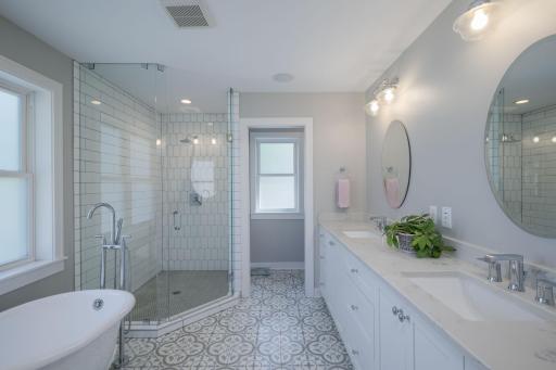 The primary bath is Pure Spa: a soaking tub, walk-in shower, dual vanities, and floor-to-ceiling tile work that turns every morning into a moment of luxury.