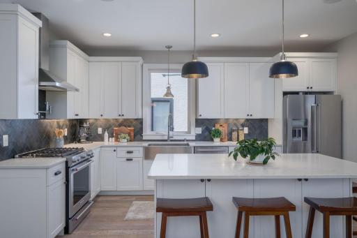 Style meets substance with the kitchen's rich backsplash tile, crisp white cabinetry, and bold pendant lighting, creating a space that is beautiful to look at as it is to cook.