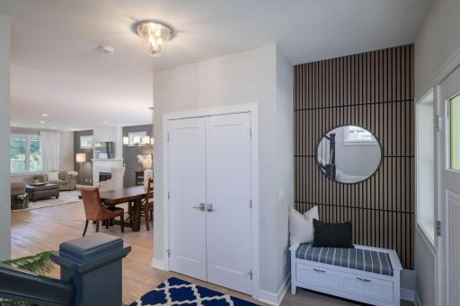 A built-in mudroom nook with a dramatic slated wood accent wall and round mirror. The kind of thoughtful design detail that sets the home apart from the moment you step inside.