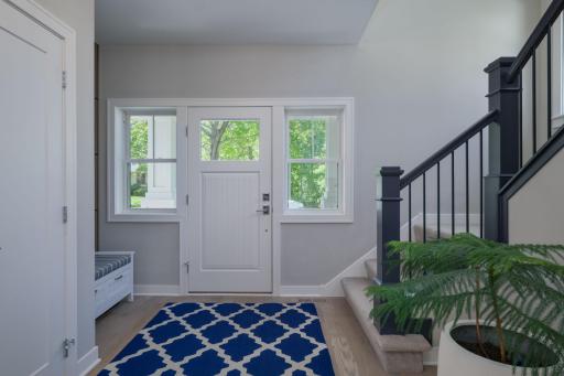 First impressions matter. A light-filled foyer with a glass panel entry door, crisp millwork, and a sweeping staircase set the tone the moment you walk in.
