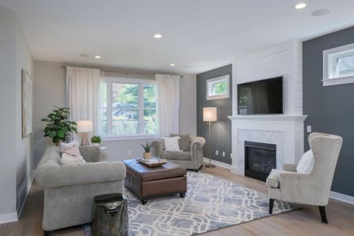 The living room is a study in relaxed elegance, with a classic fireplace, neutral palette, oversized windows, and a layout that invites you to settle in and stay a while.