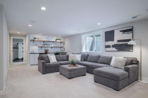 The lower level is a full entertainment destination, with a sprawling sectional, wet bar with open shelving, media wall, and egress windows that make the space as livable as any floor in the home.