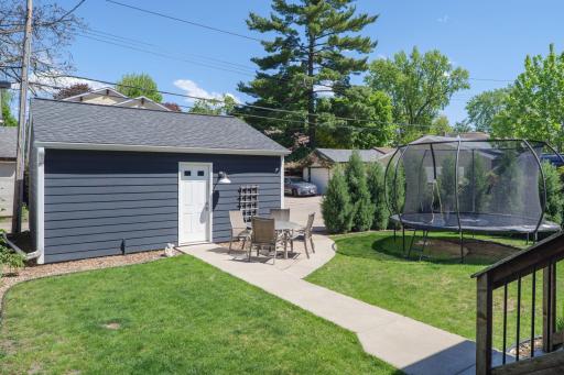 The backyard is ready for summer. A lush lawn, patio seating area, mature trees for shade, and a trampoline make this outdoor space as fun and functional as the home itself.