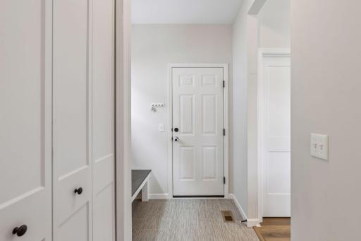 Functional mudroom off the garage with coat closet, convenient half bath access, and built-in drop zone space.
