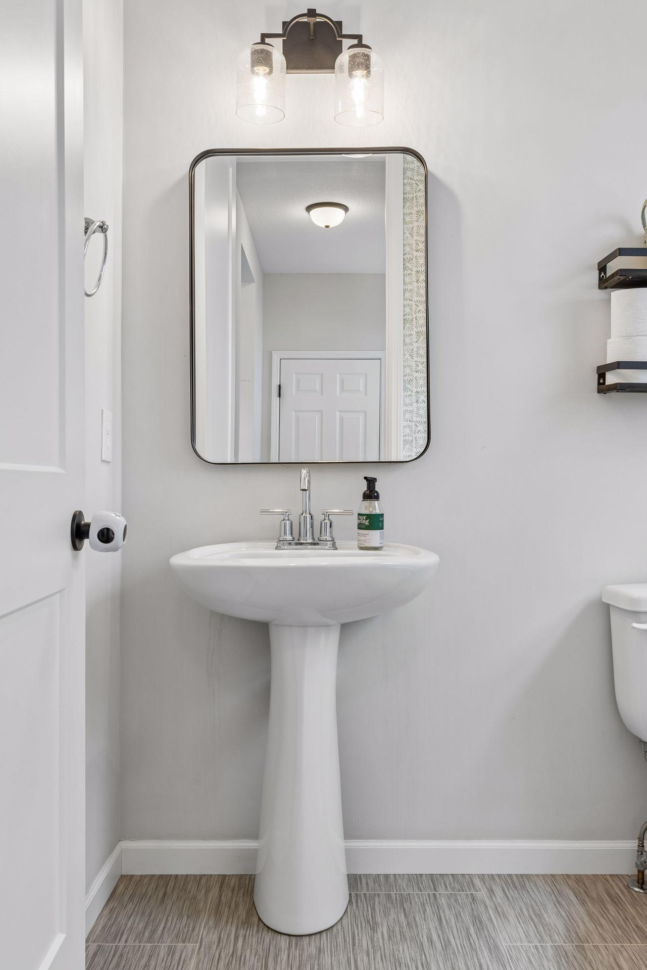 Main level half bath with updated lighting, stylish mirror, and clean modern finishes.