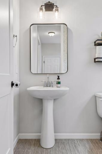 Main level half bath with updated lighting, stylish mirror, and clean modern finishes.