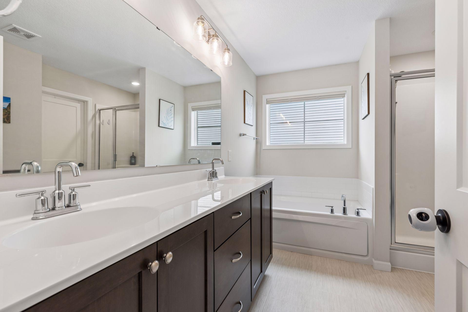 Private ensuite bath featuring dual sinks, soaking tub, separate shower, and abundant vanity space.