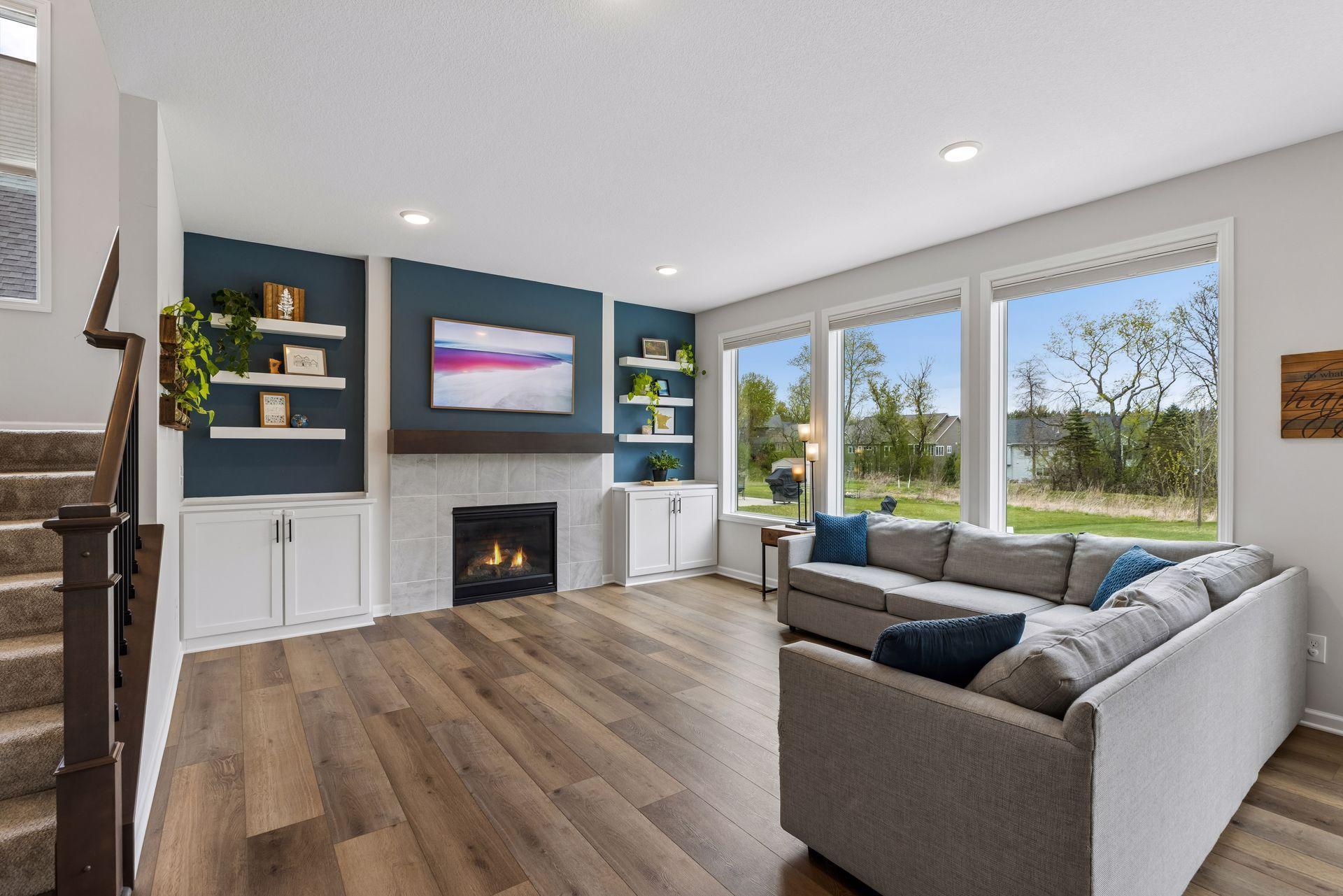Beautiful living room featuring large windows, wooded views, cozy gas fireplace, and custom built-ins for added character and storage.