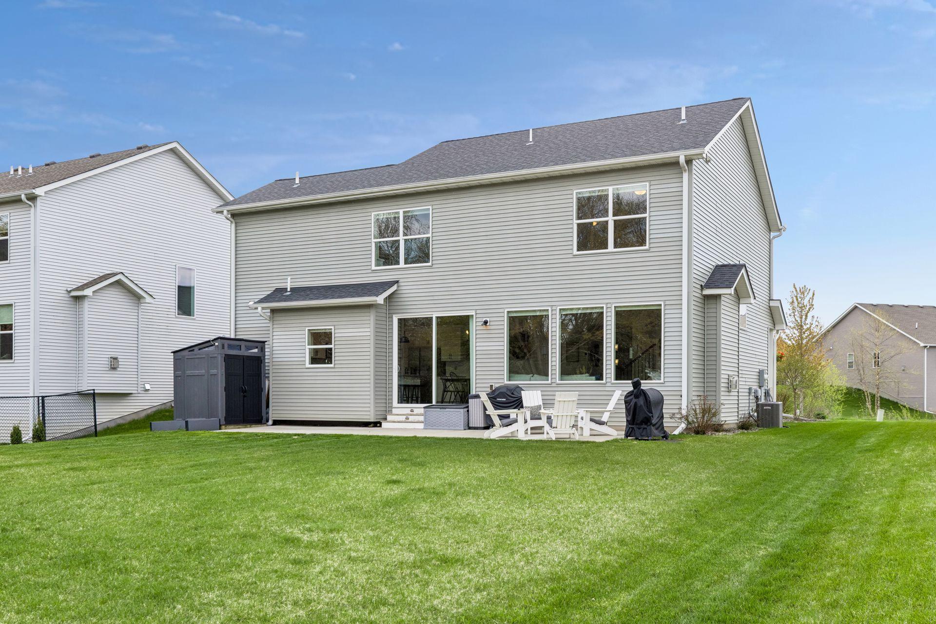 Expansive flat backyard featuring a large patio for entertaining, storage shed, and peaceful wooded backdrop.