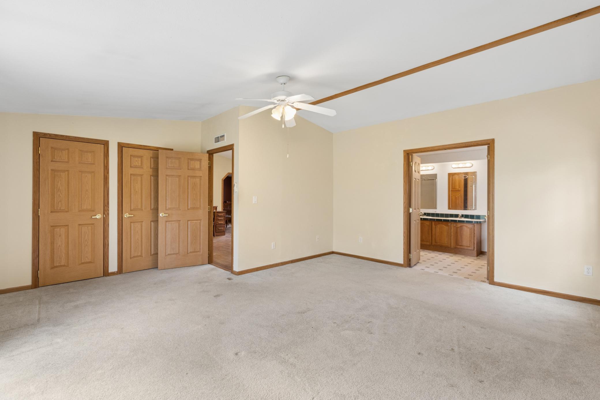 Owner's suite with private deck leading to backyard, windows overlooking pond and private bath.