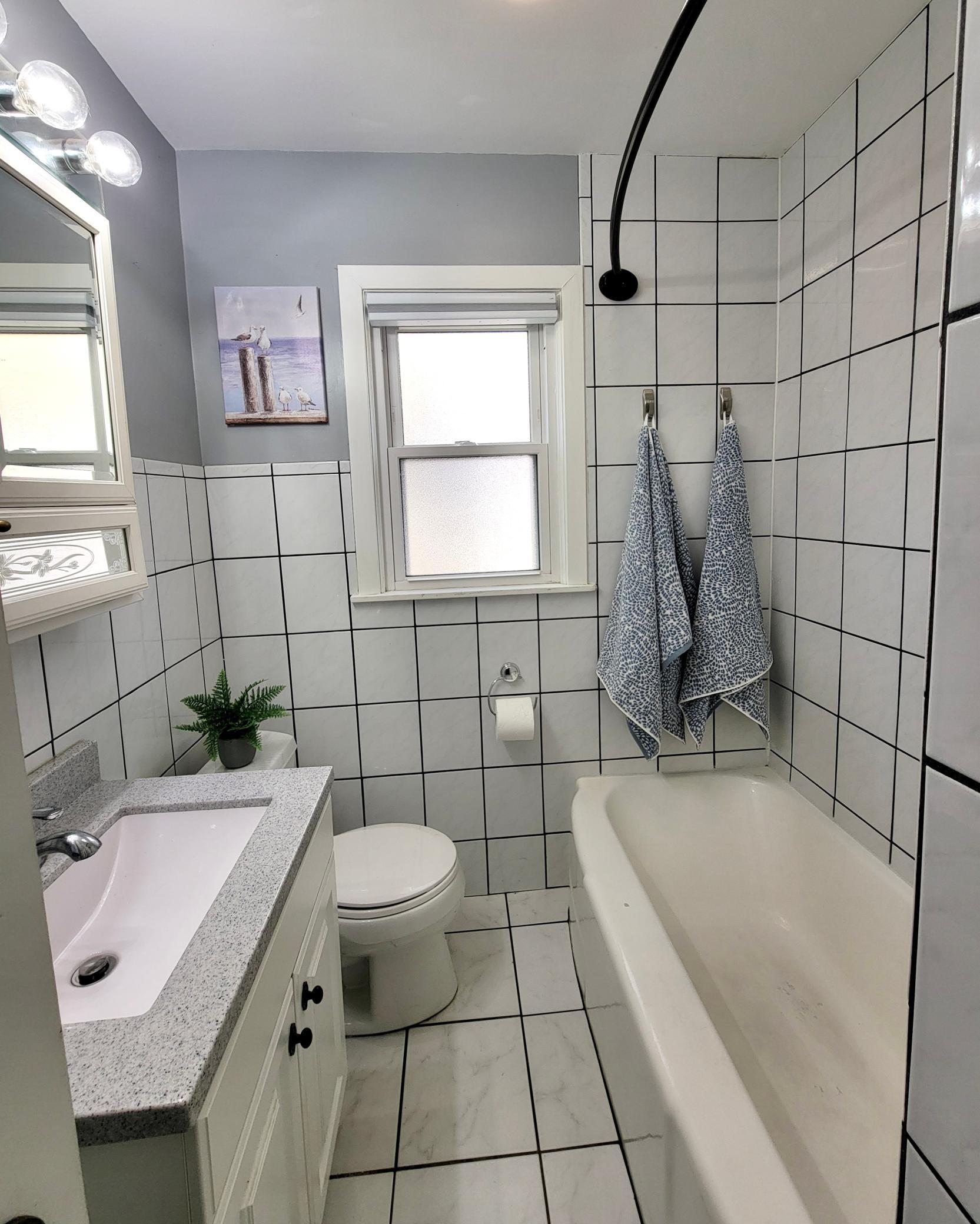 Tiled bathroom with window and linen closet storage