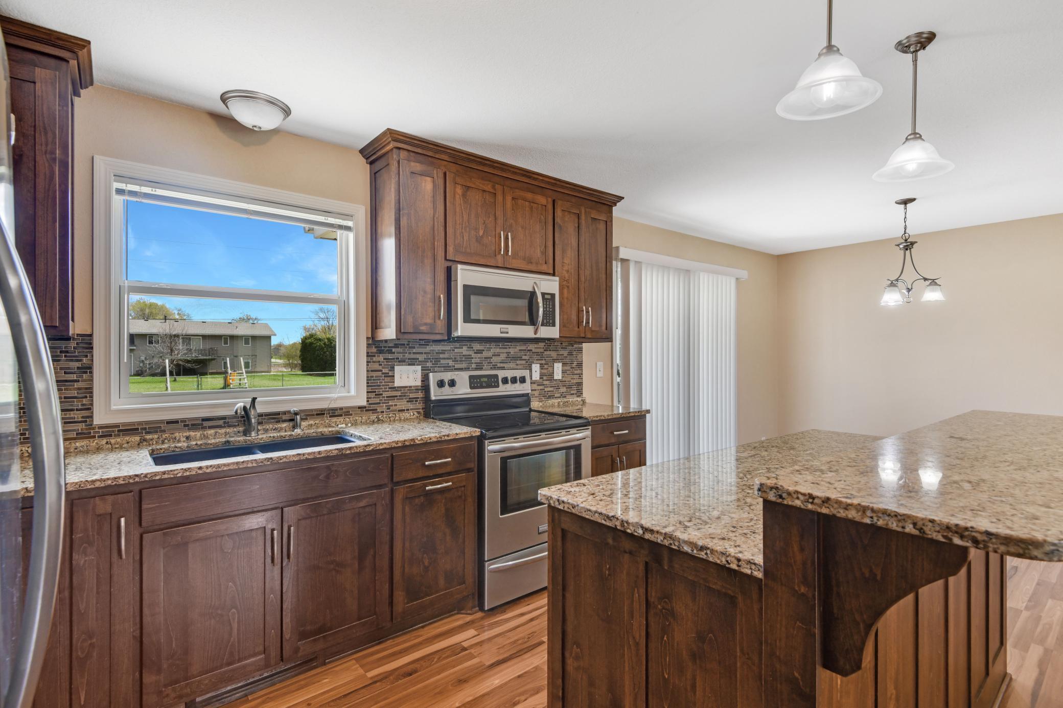 Custom Alder kitchen cabinets with center island, granite countertops, and stainless steel appliances