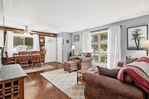 View through living room toward front entry. Beautifully updated flooring pairs seamlessly with the accent wall in the eating area.
