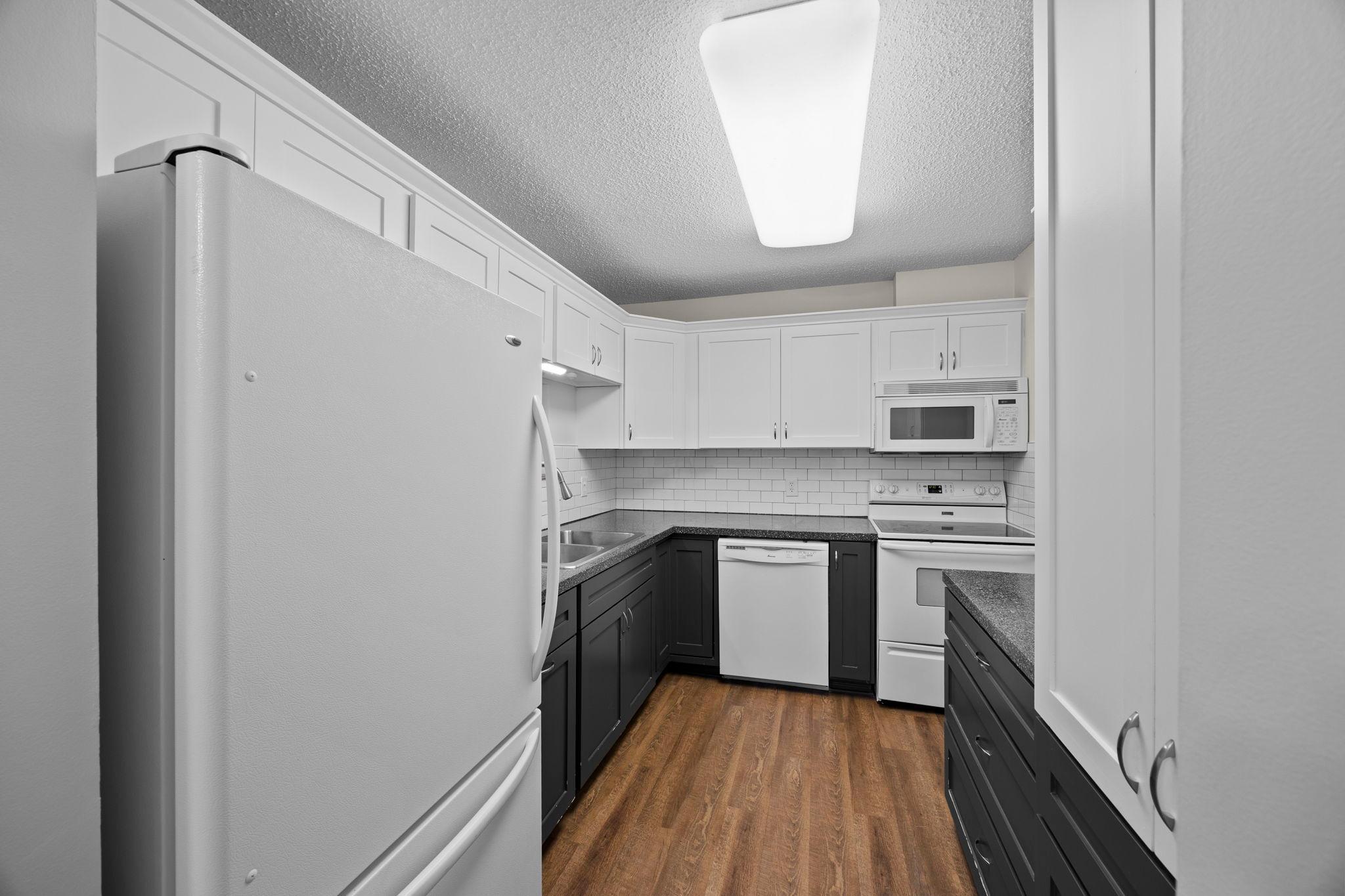 Beautiful mix of the natural wood look of LVP flooring, white cabinets and a pop of color.