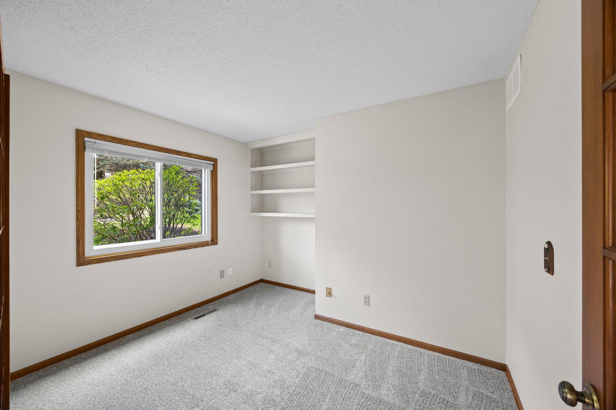 Office / Den features large window and custom bookshef or display shelving.
