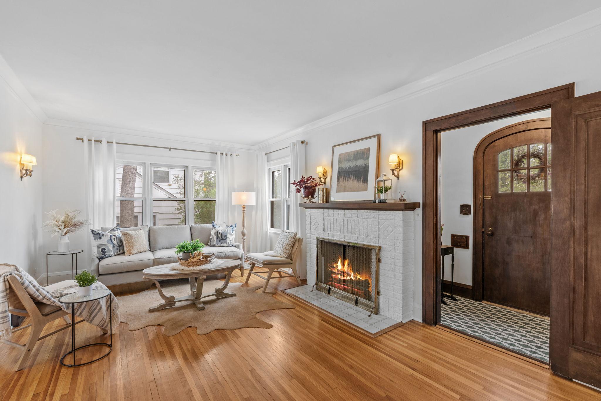 Step through the arched front entry into a warm and inviting living room filled with natural light, a cozy fireplace, and upgraded windows!