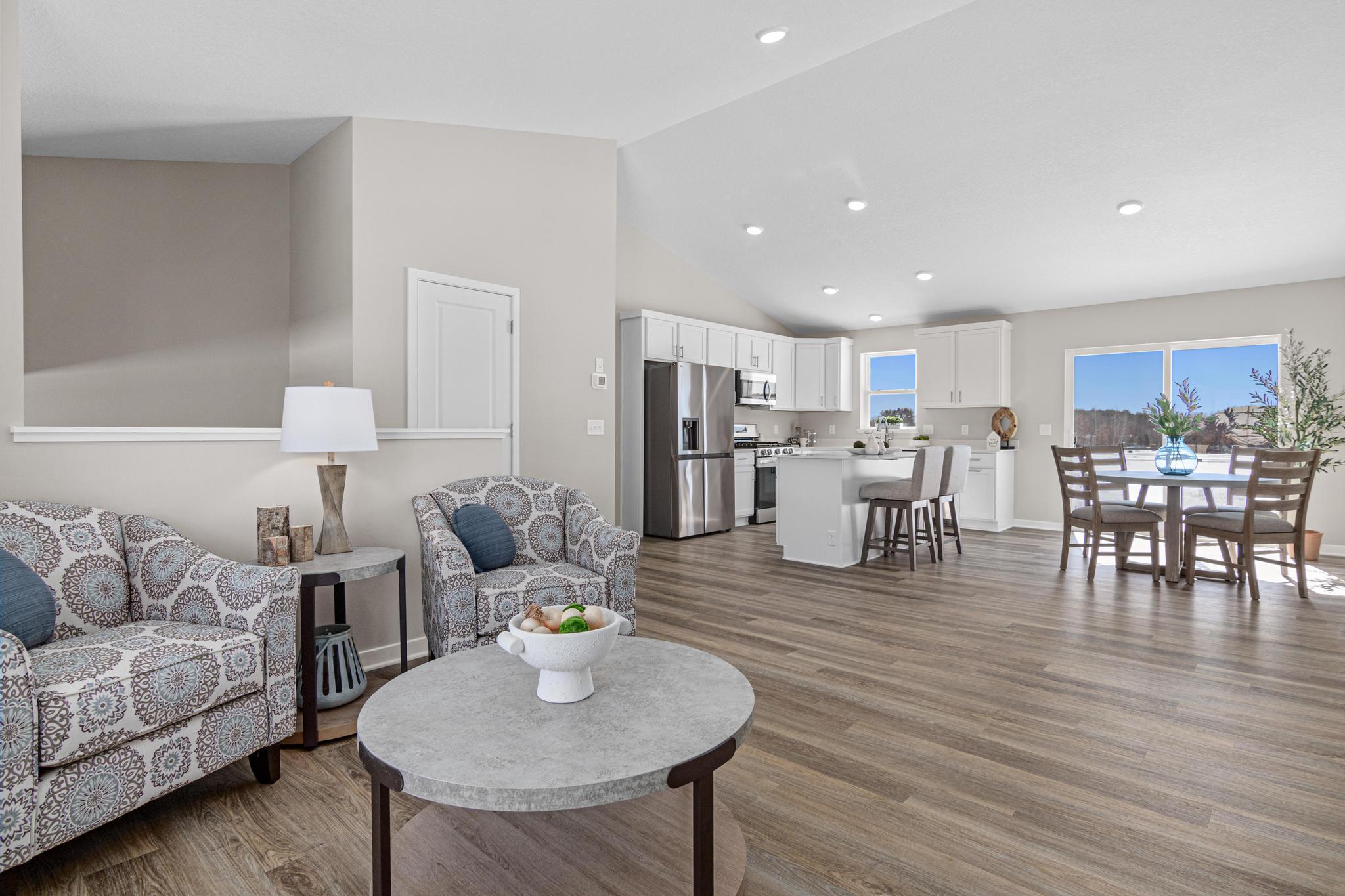 VIRTUALLY STAGED PHOTO OF A DIFFERENT HOME WITH SIMILAR PLAN & FINISHES. Vaulted Ceiling in the Great Room, Dining, and Kitchen. Photo may not depict actual plan, material, & finishes included in this home.