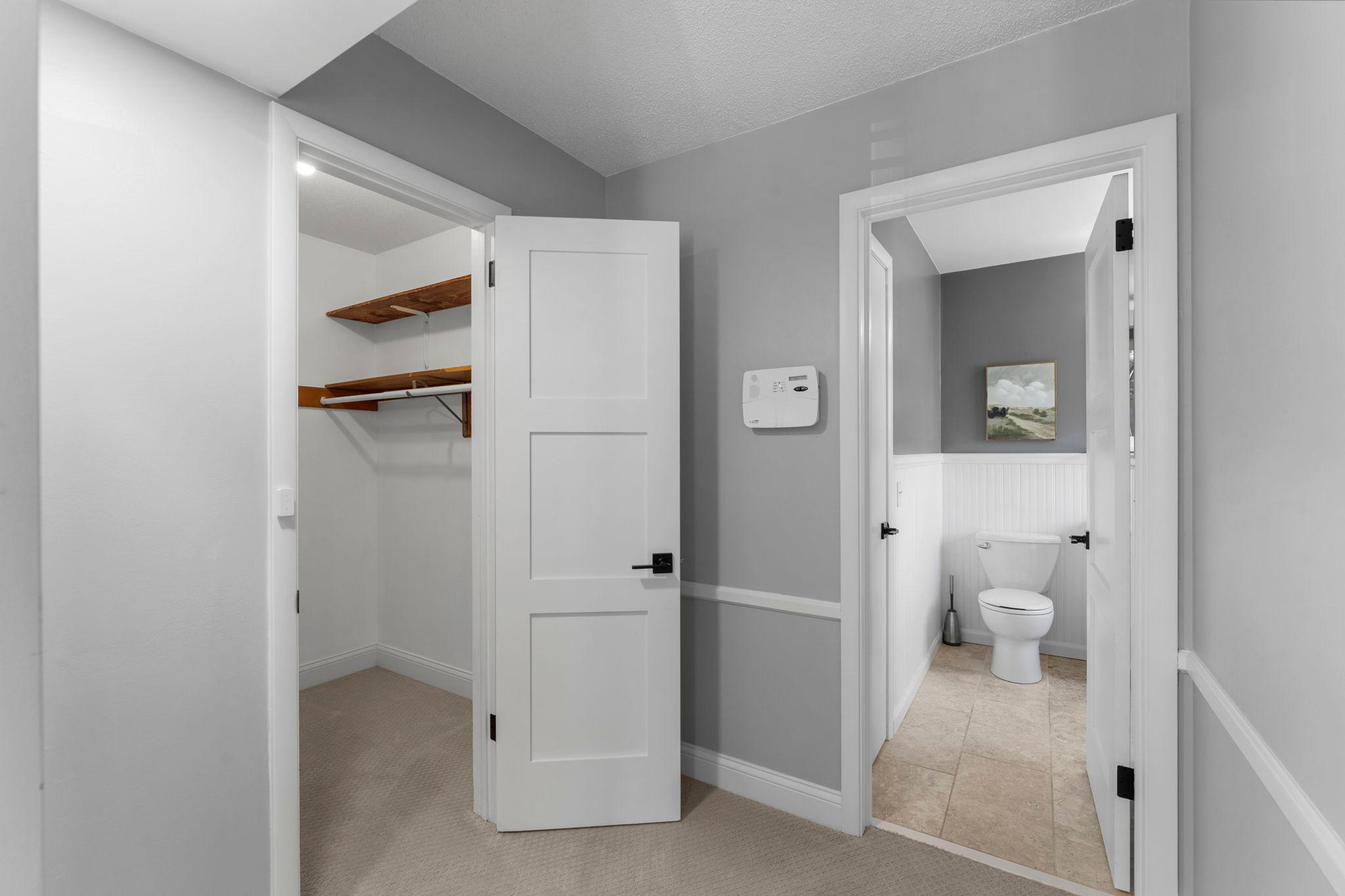 Walk-in closet with built-in shelving and a private ensuite.