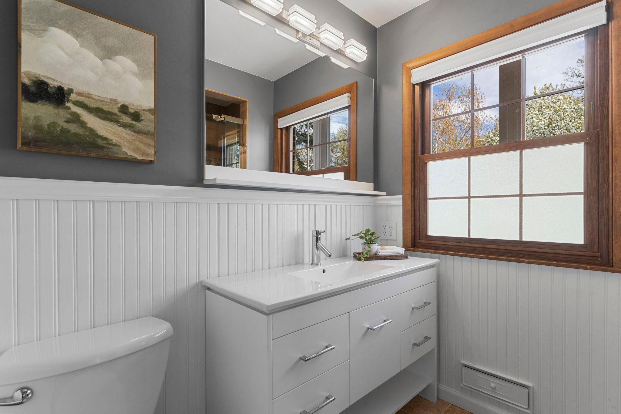 Stylish ensuite (updated in 2018) includes a tiled walk-in shower, frosted glass windows, vanity for storage, tile flooring, and a linen closet for added organization.
