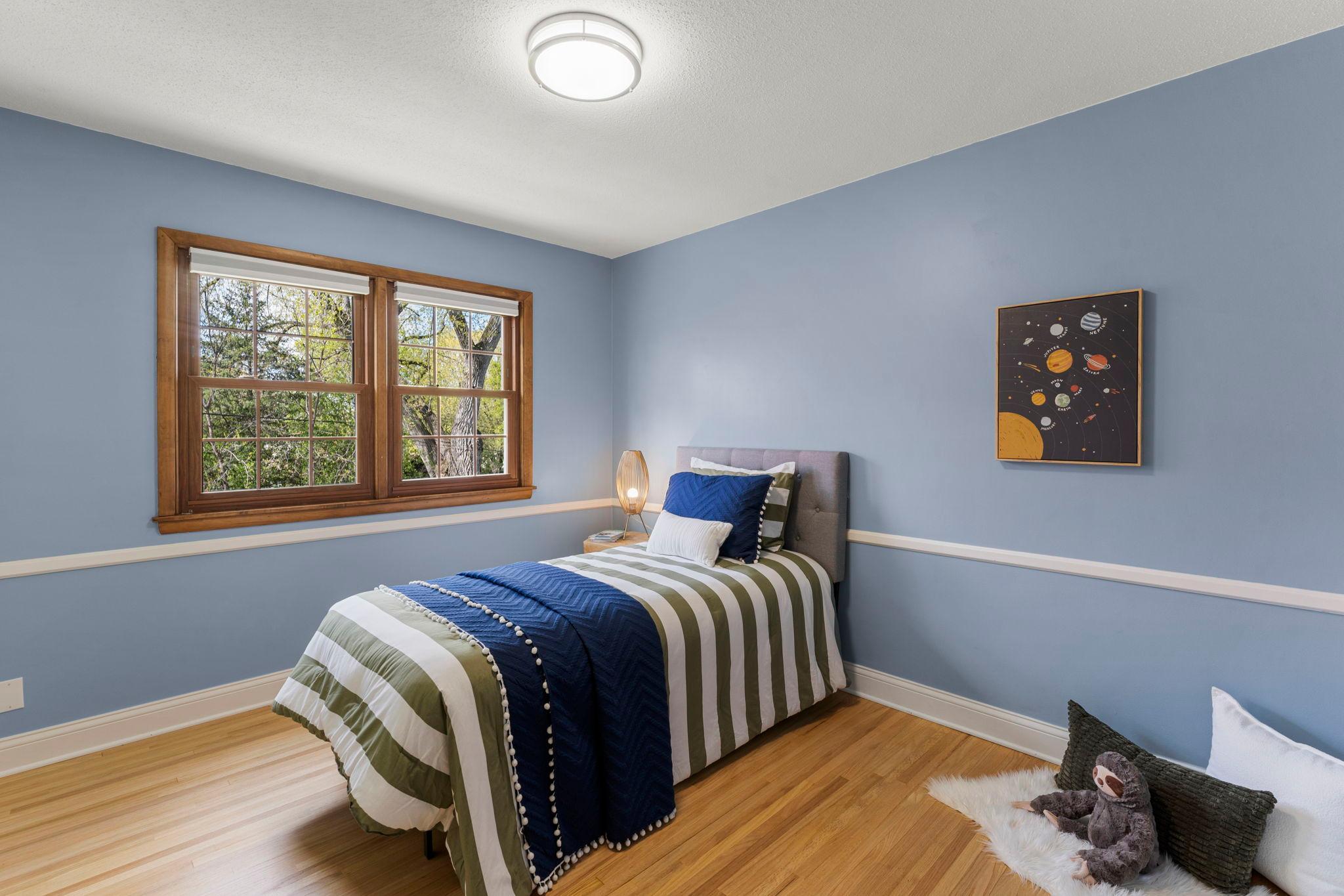 Two additional bedrooms sit nearby, each offering wood flooring and windows with serene yard views.