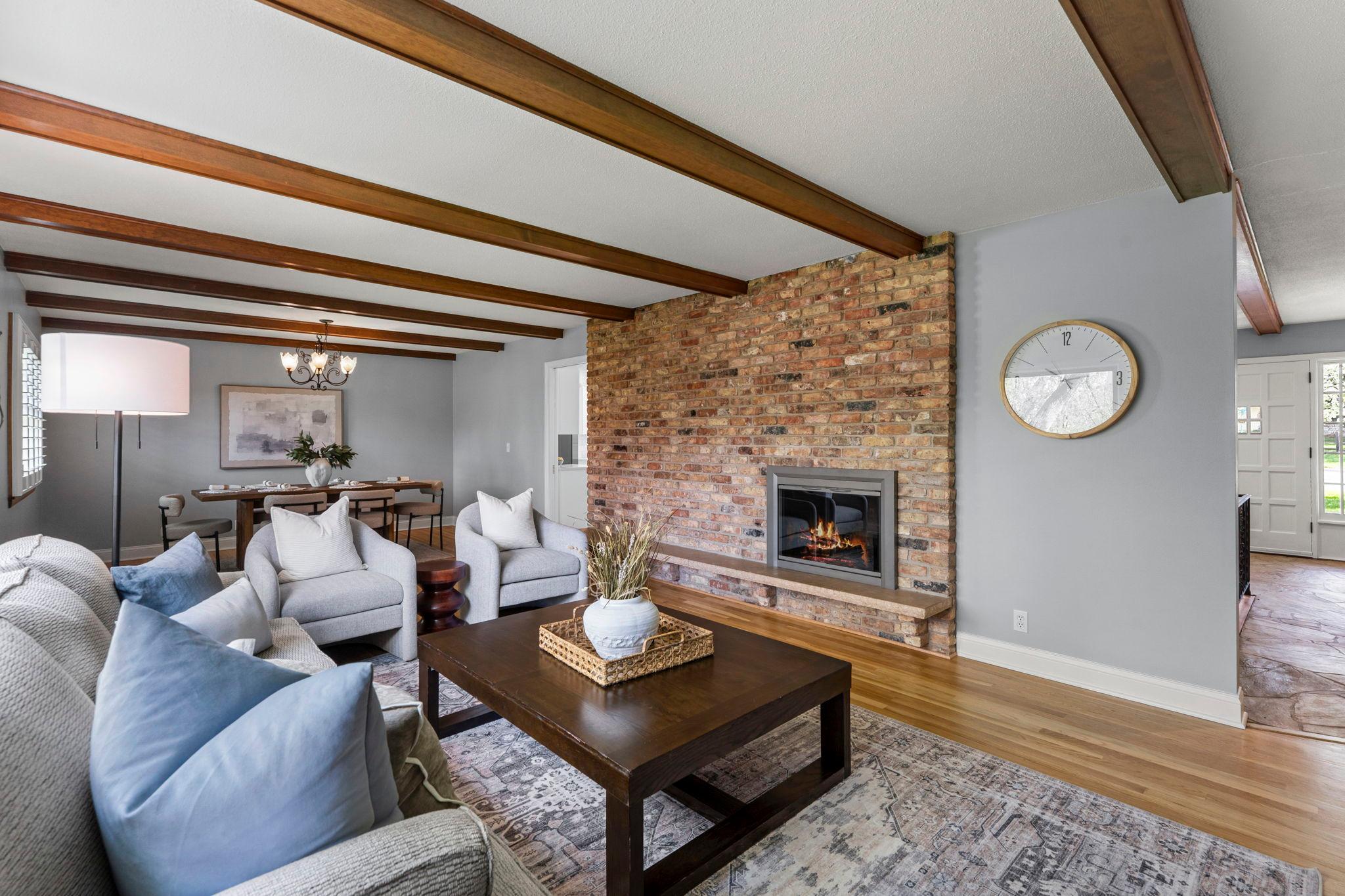 The inviting living room showcases timeless wood flooring and brick fireplace, perfect for colder Minnesota seasons.