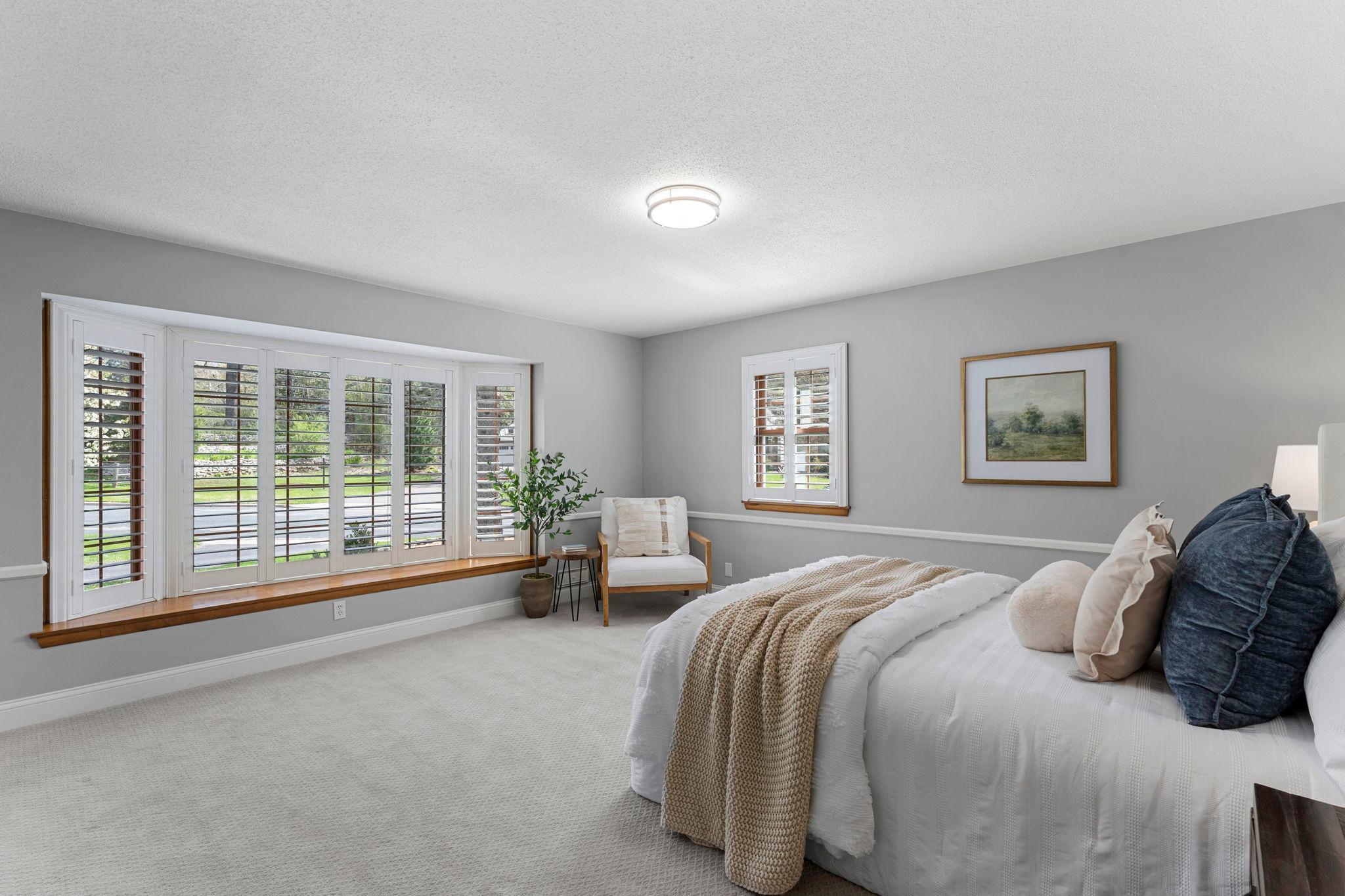 This relaxing space features soft carpeting and a large bay window with shutters for light, along with privacy.