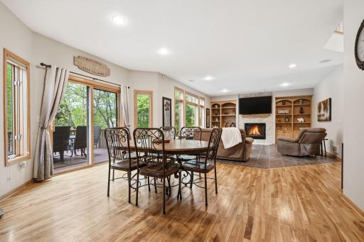 Open-concept kitchen, dining, and living area featuring sliding glass patio doors that open to a massive deck overlooking the in-ground pool, just steps from the kitchen