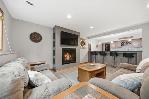 Lower-level family room featuring a cozy gas fireplace and a full bar to the rightâperfect for entertaining guests or enjoying movie nights.