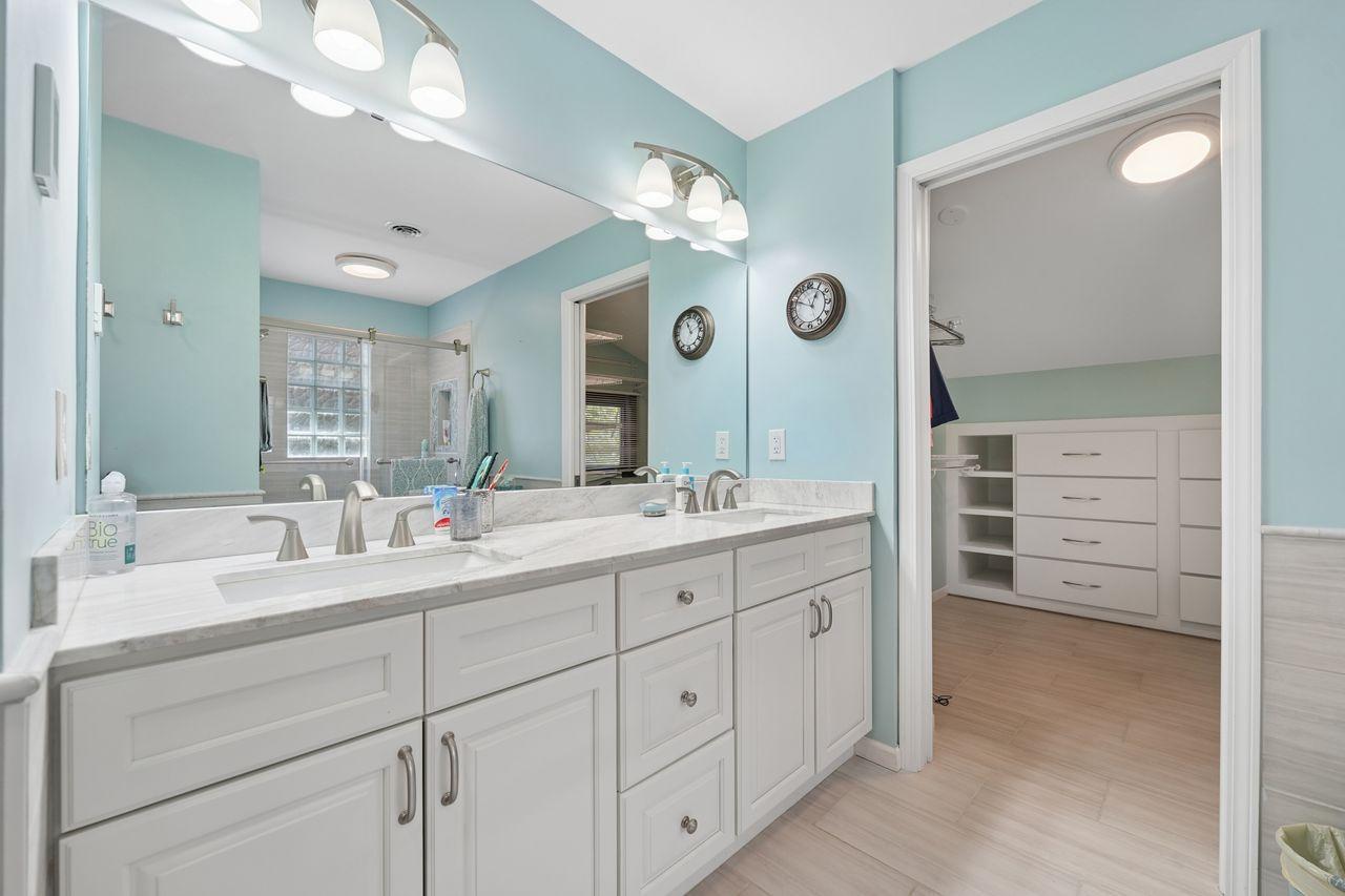 Owner suite bathroom, updated dual vanity, solid surface counters, large walk in closet with built storage, newer flooring