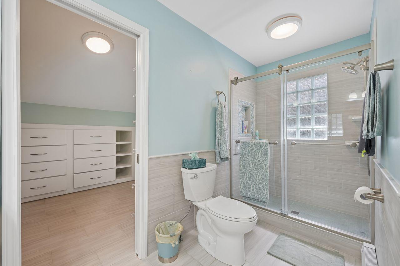 Owner suite bathroom, updated dual vanity, solid surface counters, large walk in closet with built storage, newer flooring, beautiful walk in shower, glass block for natural lighting