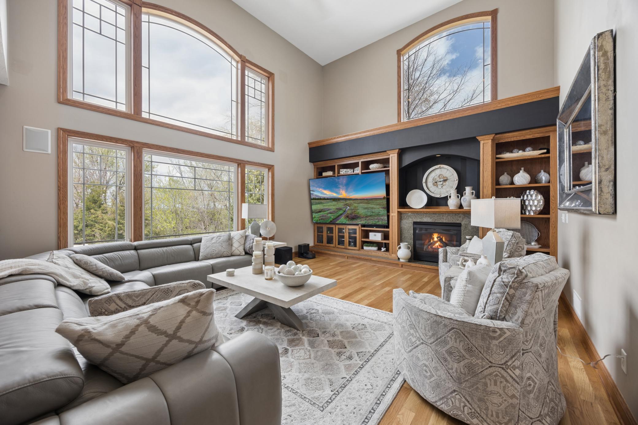 Grand living room with soaring wall of windows, fireplace, and built-in shelving.