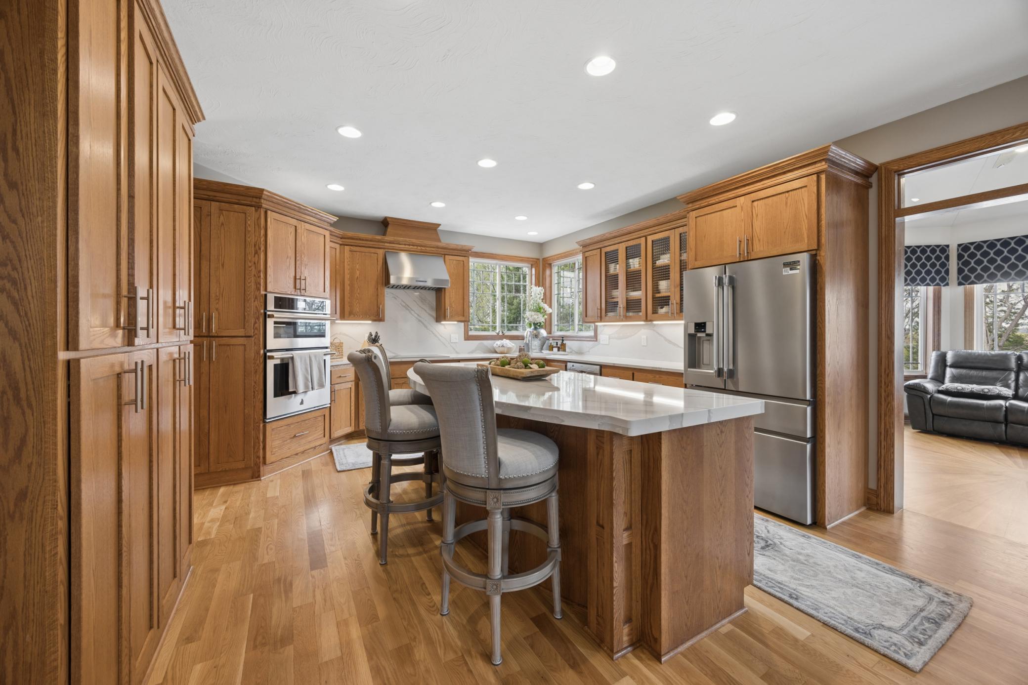 Chef’s kitchen featuring induction cooktop, double ovens, quartz counters and backsplash, and under-cabinet lighting. Designed for entertaining with abundant storage, large dining space, and a separate formal dining room.