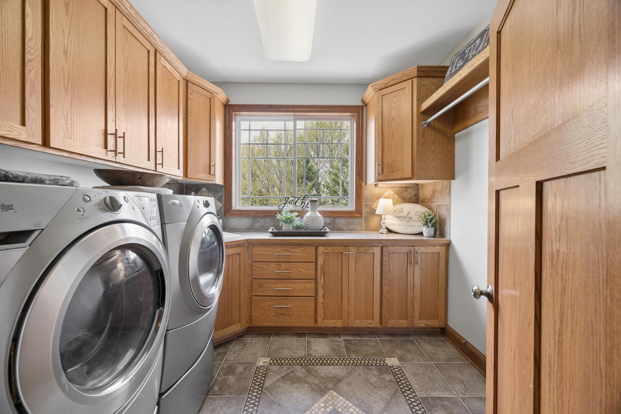 Bright and expansive main level laundry featuring generous storage, ample natural light, and convenient hanging space.