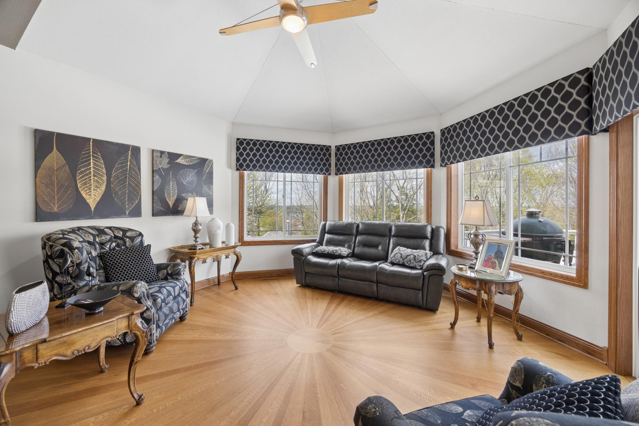 Bright, oversized sunroom with curved windows and views of the deck and pool area.