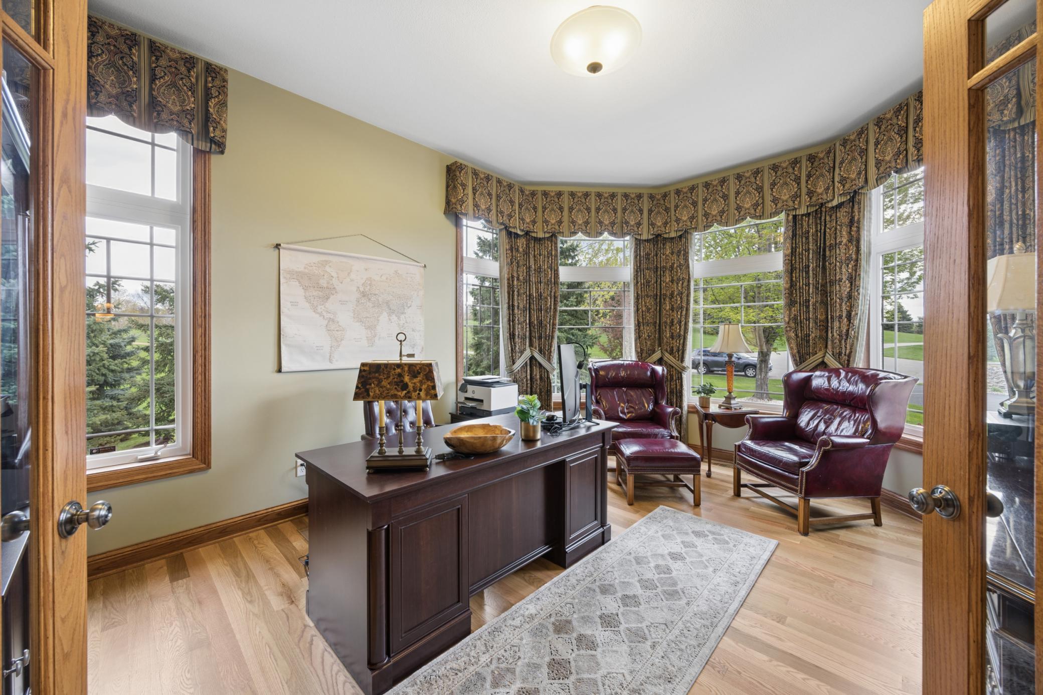 Distinguished executive office featuring a stunning curved wall of windows, rich woodwork, and an abundance of natural light—creating an inspiring and sophisticated workspace.
