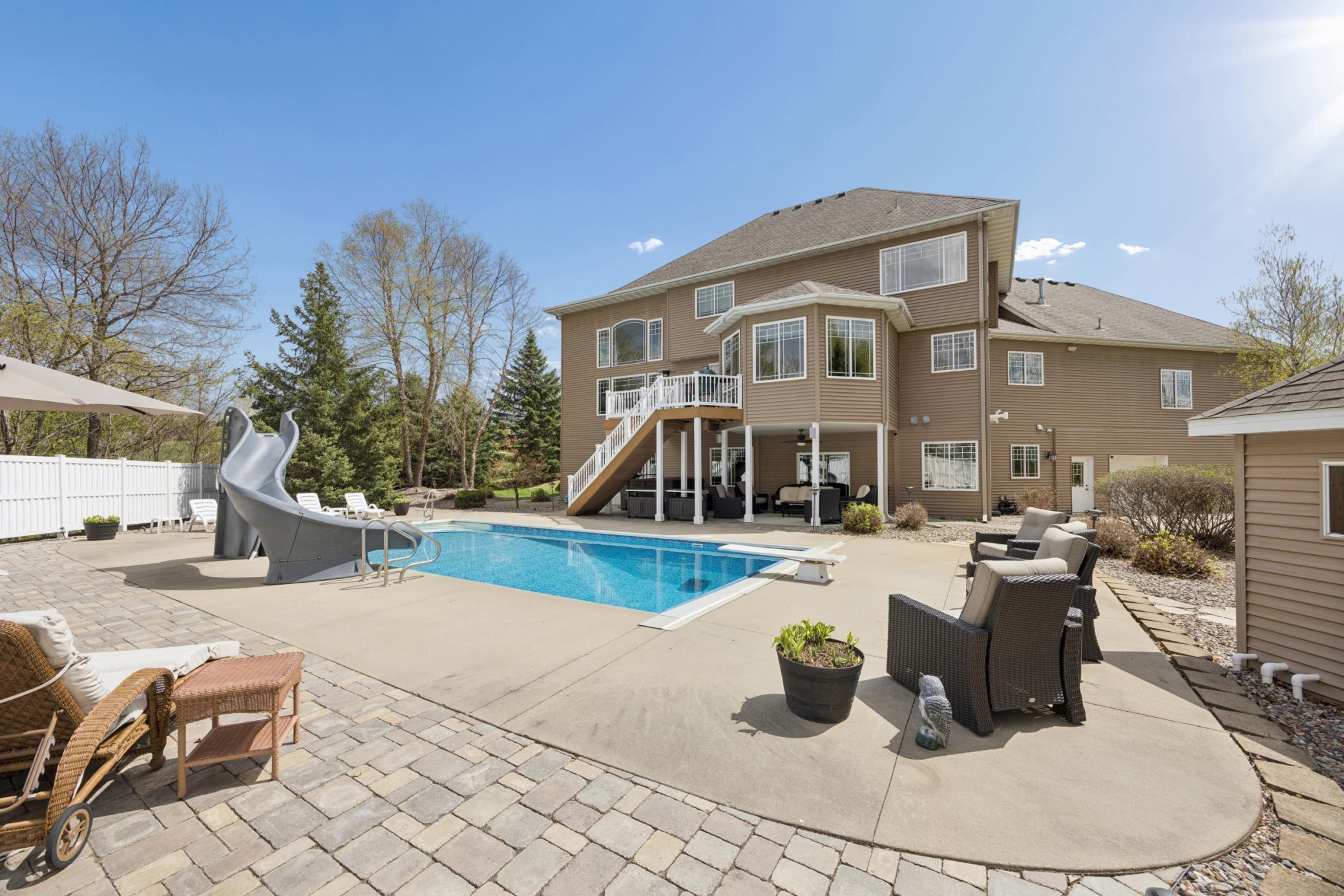 Private backyard oasis featuring pool with slide, hot tub, pool house, and beautiful landscaping within a privacy fence.