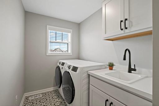 Upper level laundry room with a sink is located in the hallway