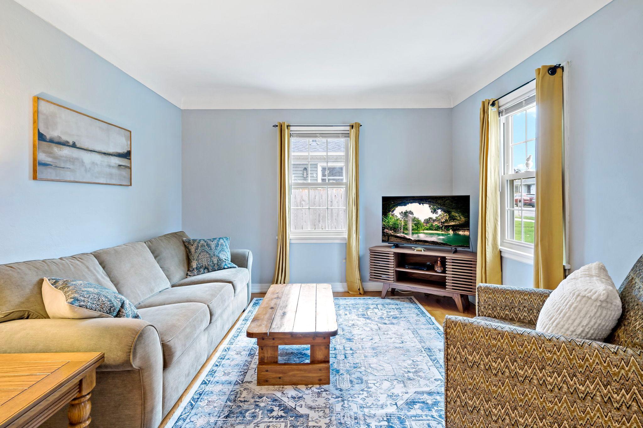 Sun-soaked main level living room features coved ceilings and hardwood floor.