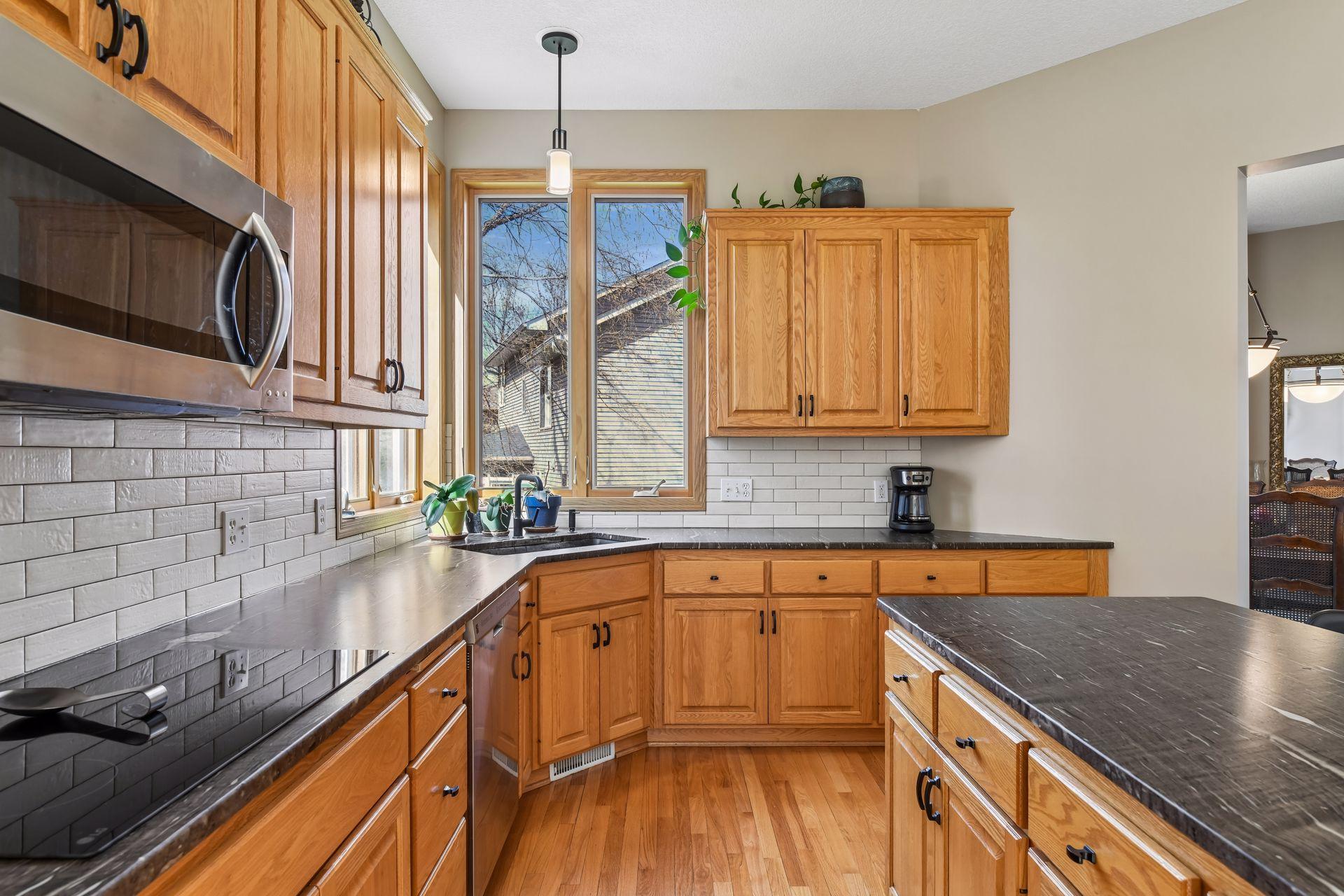 The kitchen features updated stainless steel appliances, including a built-in wall oven and glass cooktop.