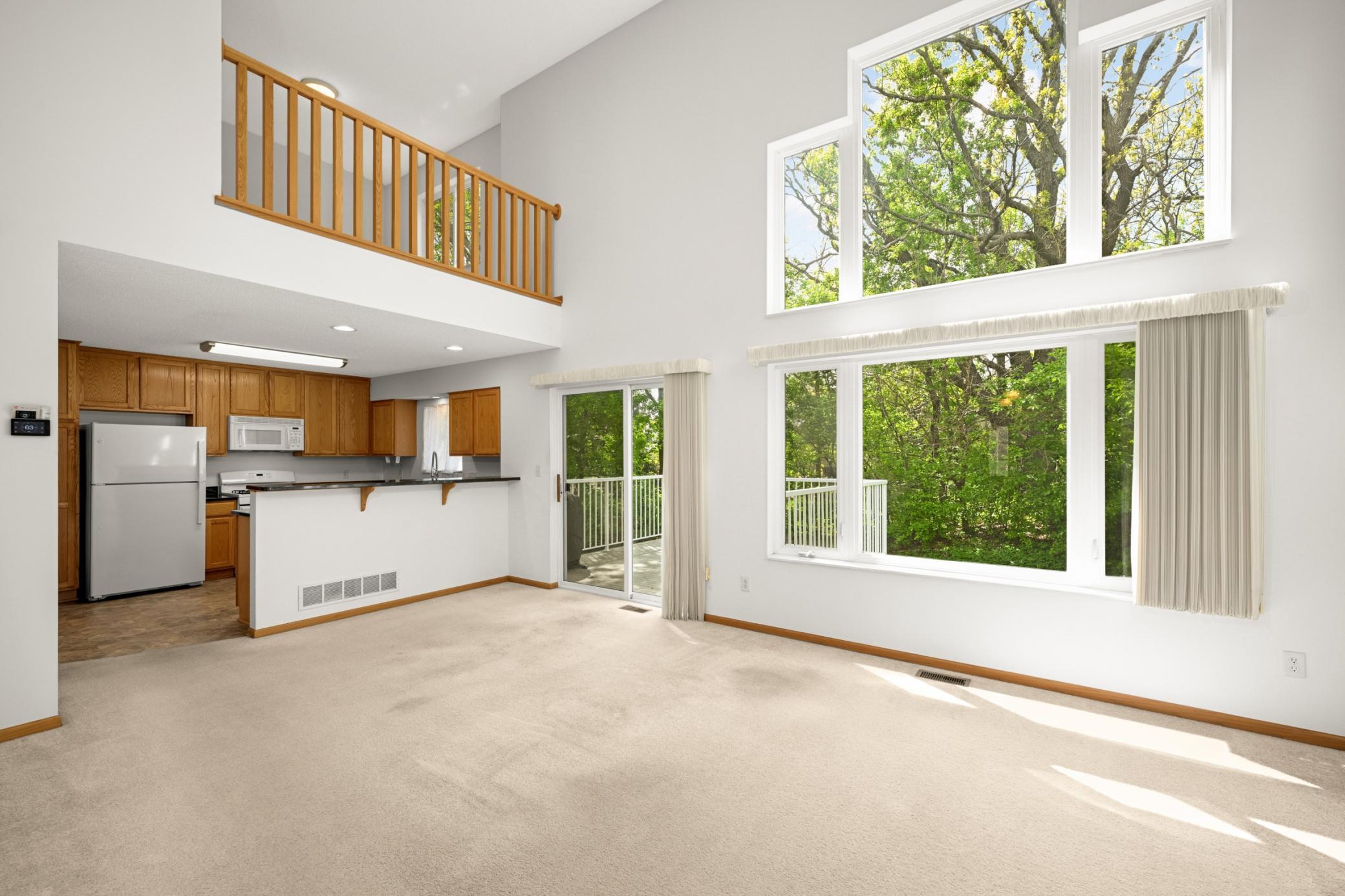 Fantastic open floor plan with a vaulted ceiling and large windows overlooking the wooded backyard