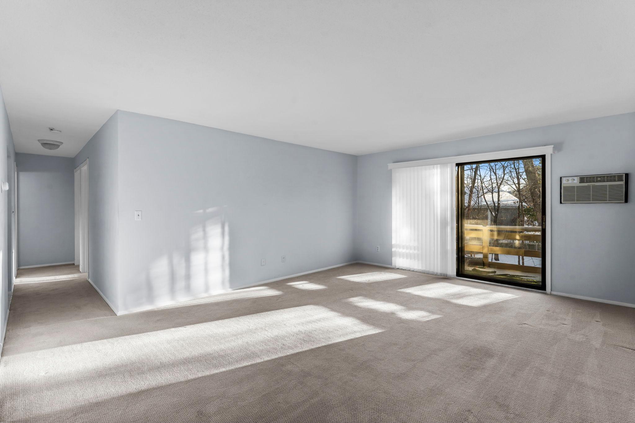 Living room with hallway on left and balcony on right