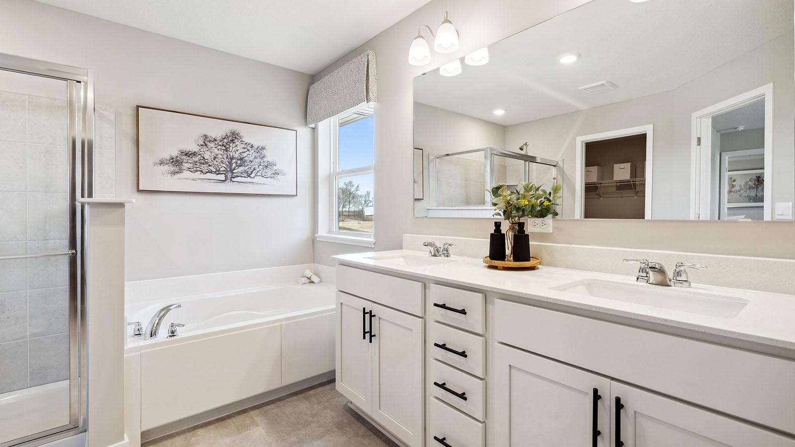 Primary bath with dual sinks, soaking tub and walk-in shower. Photo of model, colors and finishes may vary.