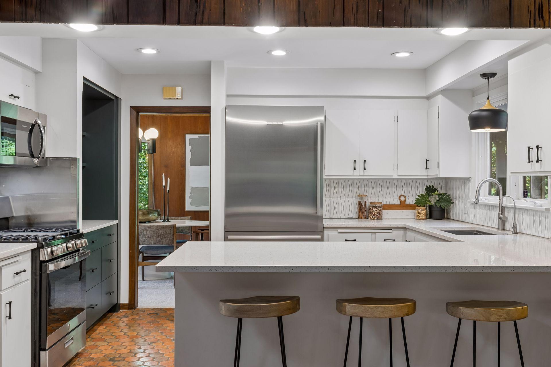 Kitchen is completely upgraded with recessed lights, pendant lighting, sink, faucet, enameled cabinets, solid stone peninsula and stainless appliances.