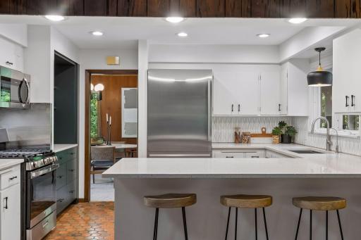 Kitchen is completely upgraded with recessed lights, pendant lighting, sink, faucet, enameled cabinets, solid stone peninsula and stainless appliances.