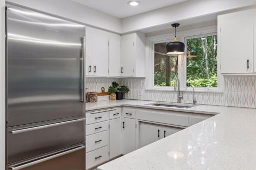 Kitchen completely upgraded with newer sink, faucet pendant light at window overlooking backyard area. New curated tile backsplash in the fabulous MCM style