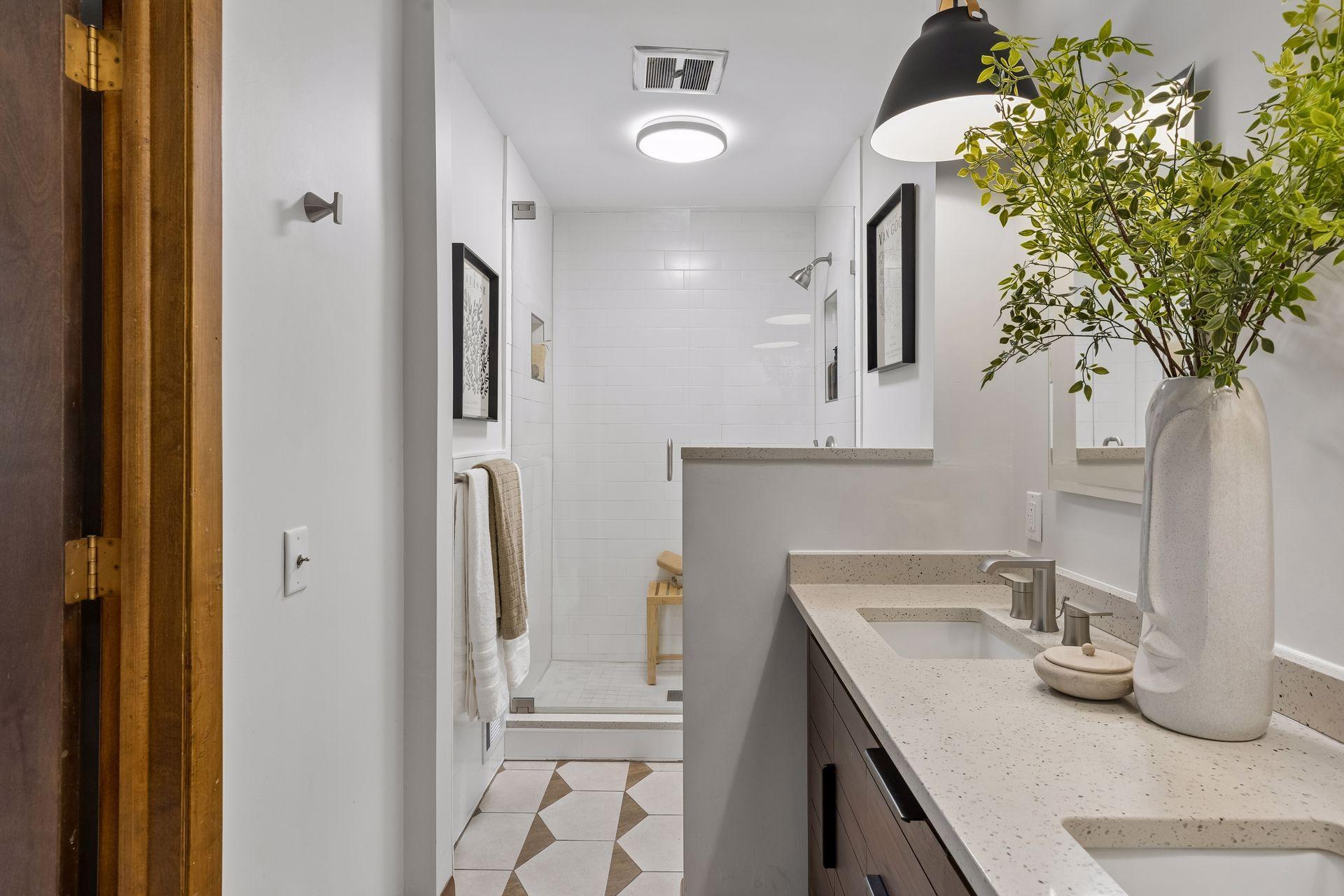 Completely remodeled primary bath with custom tile floor, glass shower surround, dual sinks and new lighting and fixtures.