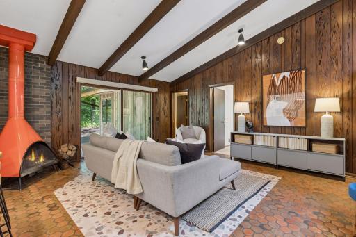 Kitchen opens to family room. Original hex-tiles in signature MCM style. Steel fireplace with bricked corner detail.