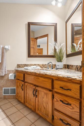 Detailed look at the en suite vanity area, highlighted by elegant fixtures, dual mirrors, and neutral tile flooring.
