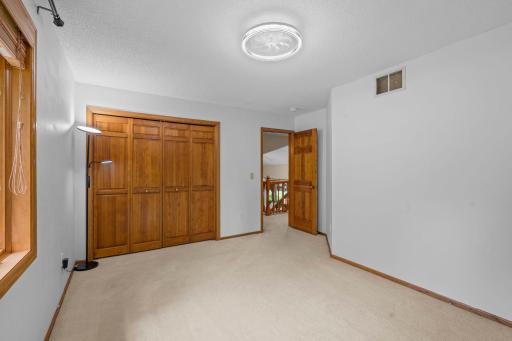 Alternate view of the second bedroom showcasing the excellent closet space and a modern ceiling fan.