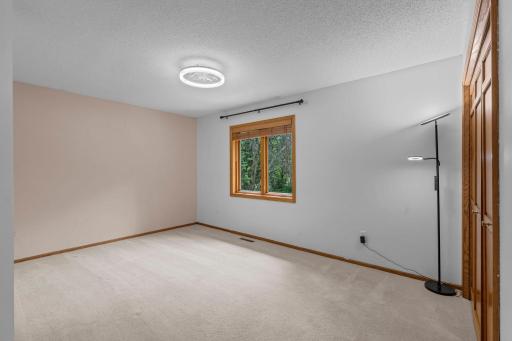 Generously sized second bedroom featuring crisp walls, neutral carpeting, and a large window facing the yard.
